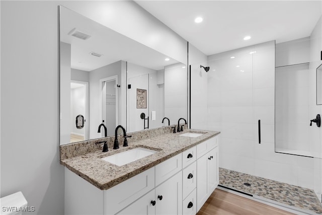 bathroom with vanity, hardwood / wood-style floors, and tiled shower