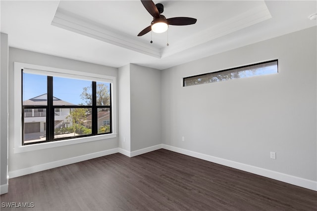 unfurnished room with a raised ceiling, ceiling fan, and dark hardwood / wood-style floors