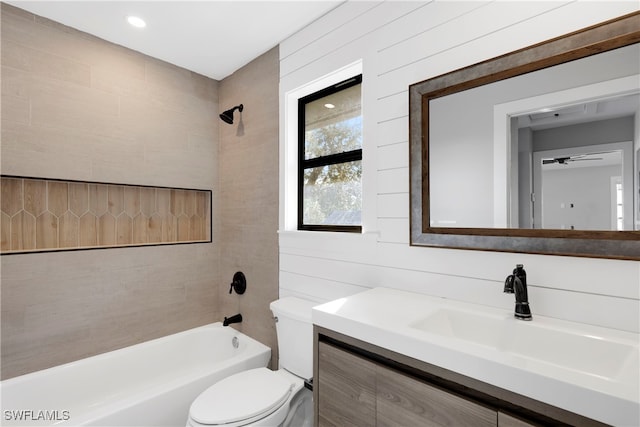 full bathroom featuring toilet, vanity, ceiling fan, tiled shower / bath, and wooden walls