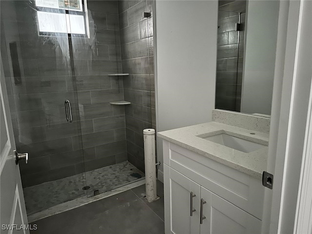 bathroom featuring a shower with shower door and vanity