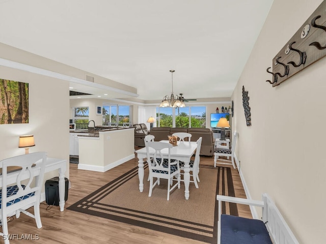 dining room with sink, light hardwood / wood-style flooring, and a chandelier