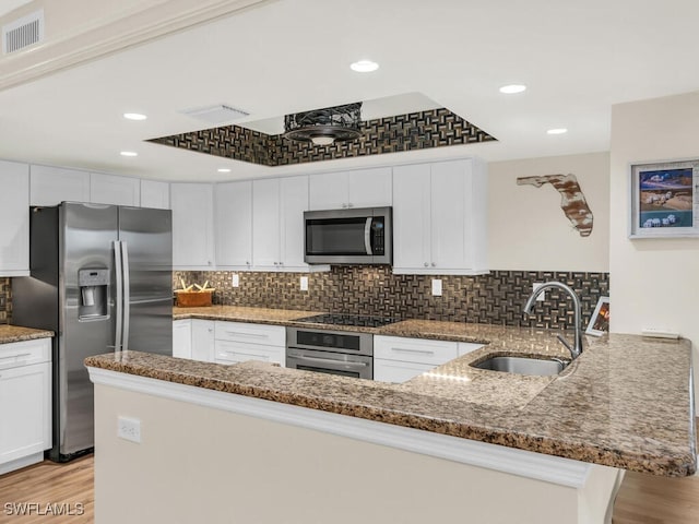 kitchen featuring kitchen peninsula, sink, white cabinets, stone counters, and stainless steel appliances