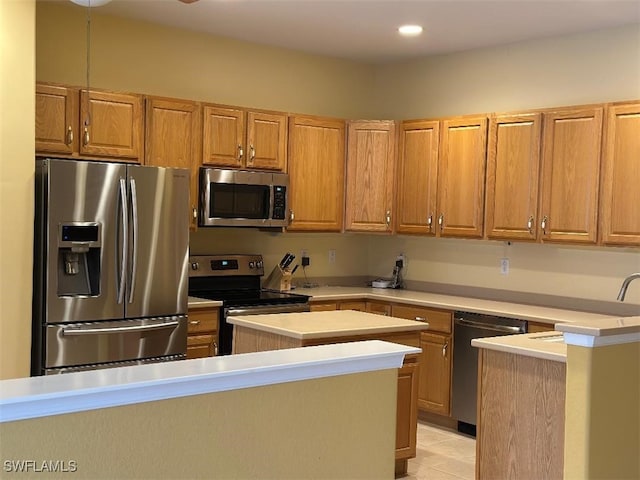 kitchen featuring stainless steel appliances, brown cabinetry, light countertops, and a kitchen island