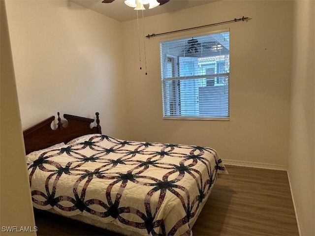 bedroom with dark wood-type flooring, ceiling fan, and baseboards