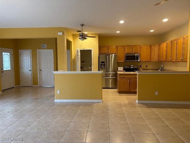 kitchen featuring an island with sink, brown cabinets, stainless steel appliances, light countertops, and recessed lighting