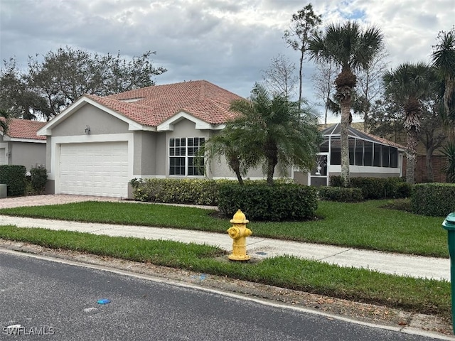 view of front of home with a tile roof, stucco siding, an attached garage, a front yard, and driveway