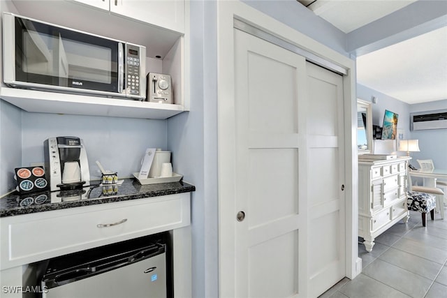 bar with white cabinets, an AC wall unit, dark stone countertops, and light tile patterned flooring