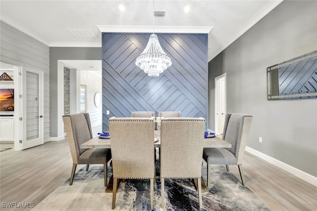 dining room featuring light wood-type flooring, an inviting chandelier, and ornamental molding