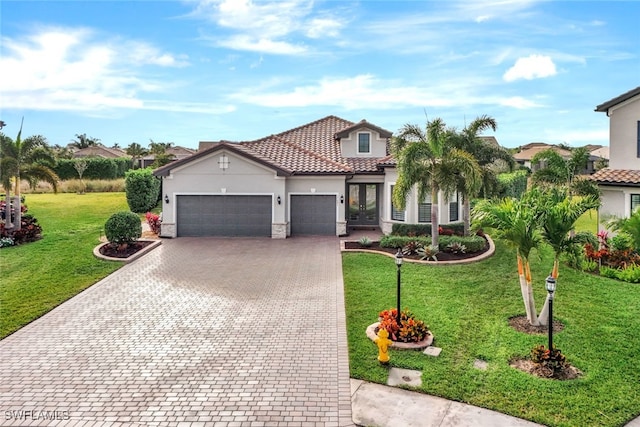 mediterranean / spanish-style house with a garage, french doors, and a front lawn