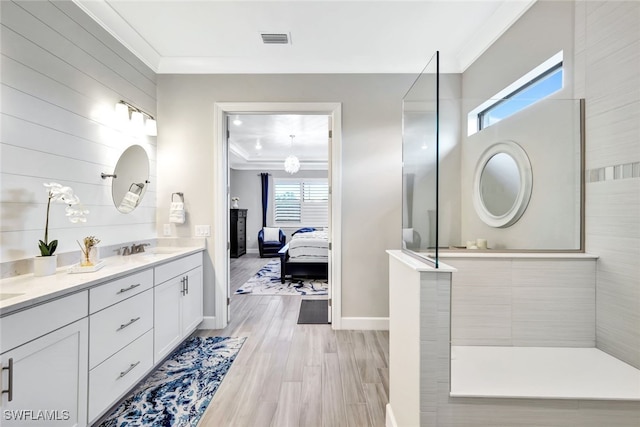 bathroom with hardwood / wood-style flooring, tiled shower, vanity, and crown molding