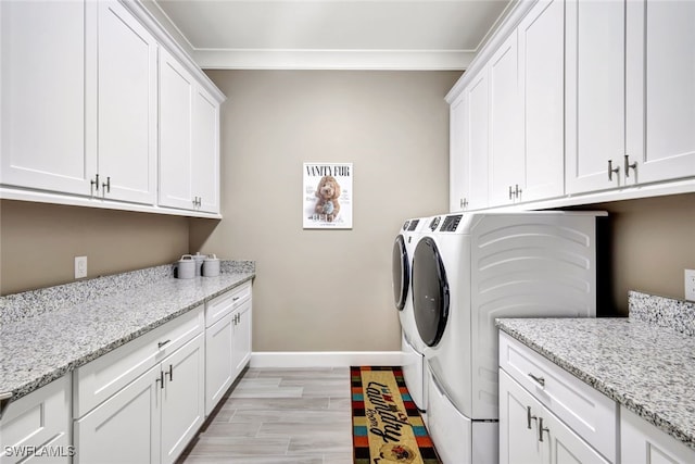 washroom featuring cabinets, washing machine and dryer, and light wood-type flooring