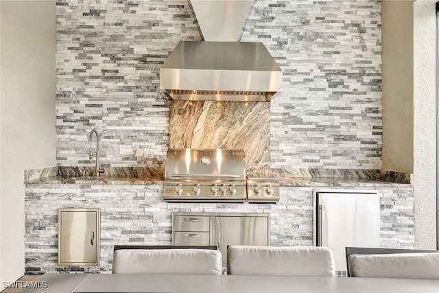 interior space featuring stainless steel refrigerator, indoor bar, and wall chimney range hood