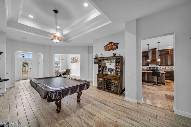 recreation room featuring billiards, light hardwood / wood-style floors, crown molding, an inviting chandelier, and a tray ceiling