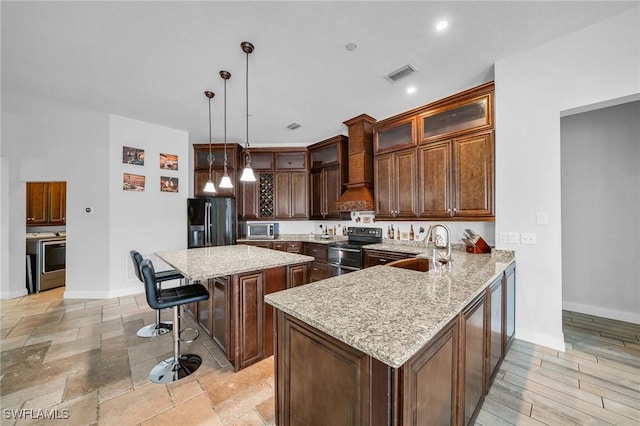 kitchen featuring decorative light fixtures, stainless steel appliances, sink, kitchen peninsula, and light stone counters