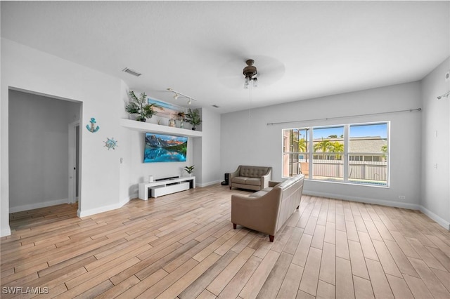 living room with ceiling fan, rail lighting, and light hardwood / wood-style floors