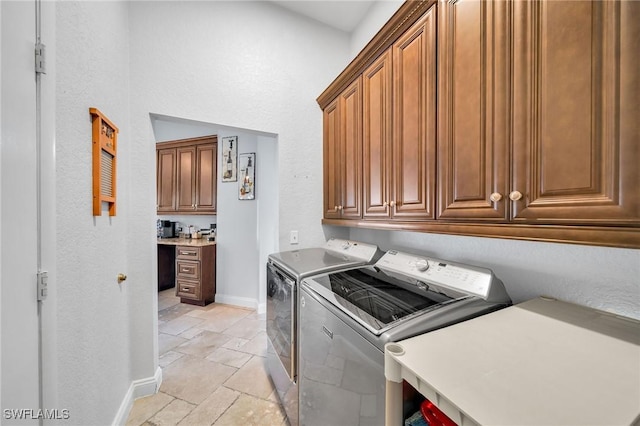 clothes washing area featuring cabinets and washer and clothes dryer