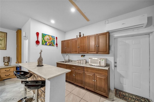 kitchen with a wall unit AC, a kitchen island, a kitchen bar, sink, and light tile patterned floors