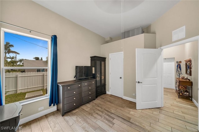 bedroom featuring light hardwood / wood-style flooring and a towering ceiling