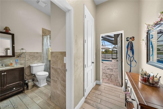 bathroom with tile walls, toilet, vanity, and a shower with curtain