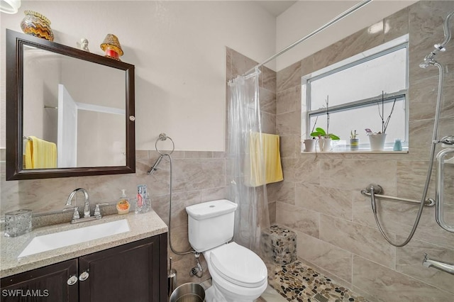 bathroom with toilet, tile walls, vanity, and curtained shower