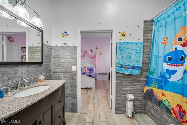 bathroom with walk in shower, vanity, tile walls, and wood-type flooring