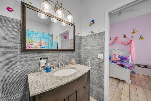 bathroom with ceiling fan, tile walls, and vanity