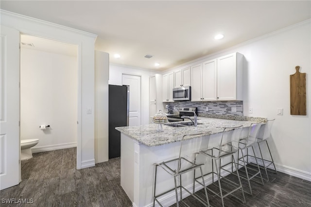 kitchen with kitchen peninsula, stainless steel appliances, white cabinets, and a breakfast bar