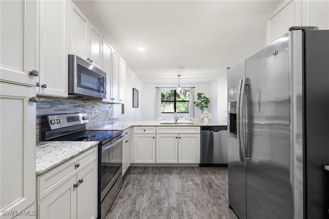 kitchen featuring white cabinetry, appliances with stainless steel finishes, backsplash, decorative light fixtures, and sink