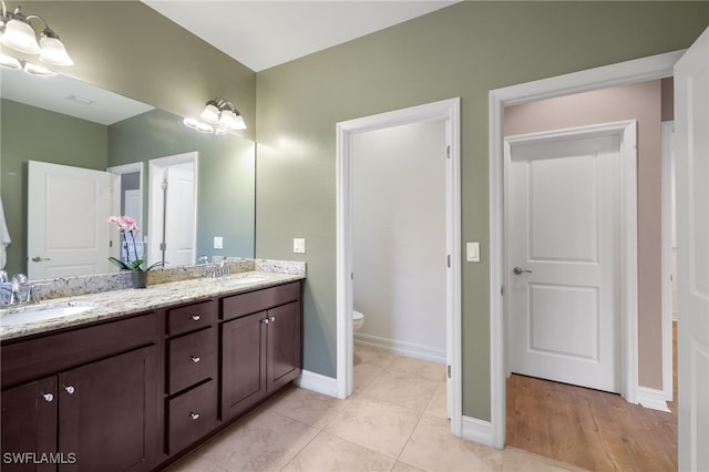 bathroom featuring toilet, vanity, tile patterned flooring, and a notable chandelier