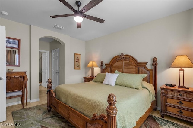 tiled bedroom with baseboards, visible vents, arched walkways, and a ceiling fan