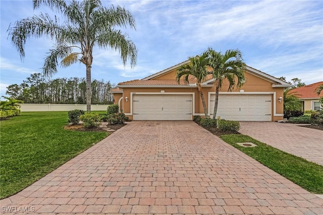 view of front of house with a garage, a front yard, decorative driveway, and stucco siding