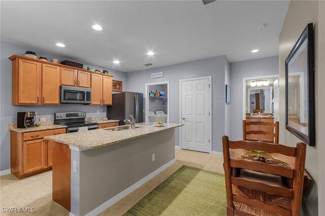 kitchen featuring light tile patterned flooring, sink, stainless steel appliances, and an island with sink