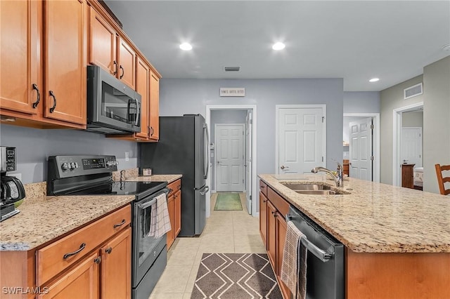 kitchen with a center island with sink, sink, light tile patterned flooring, light stone countertops, and stainless steel appliances