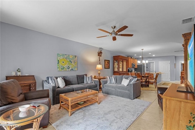 living area featuring ceiling fan with notable chandelier, visible vents, and light tile patterned flooring