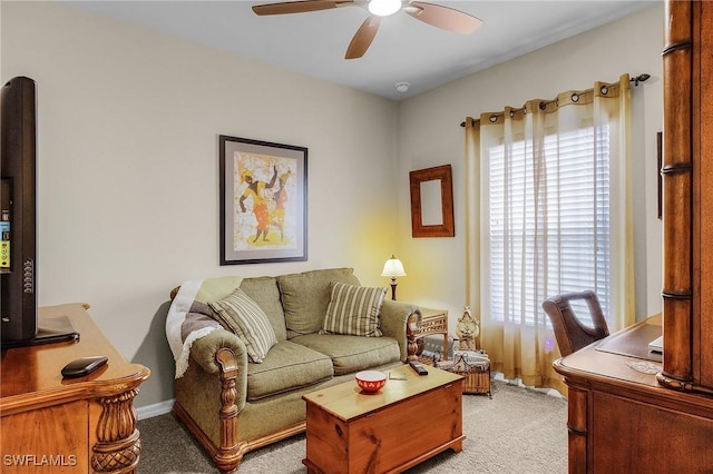 living area with a ceiling fan, light colored carpet, and baseboards