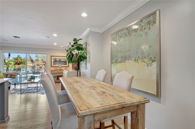 dining room with wood-type flooring and crown molding