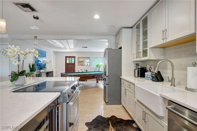 kitchen with white cabinetry, stainless steel appliances, backsplash, hanging light fixtures, and sink