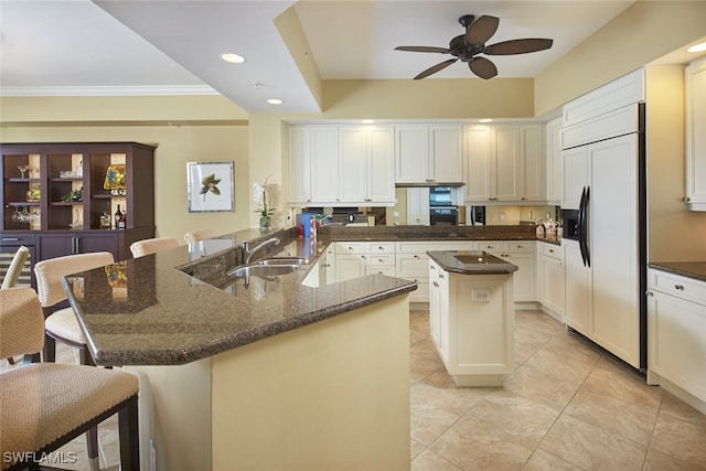 kitchen featuring sink, paneled fridge, kitchen peninsula, a kitchen island with sink, and a breakfast bar