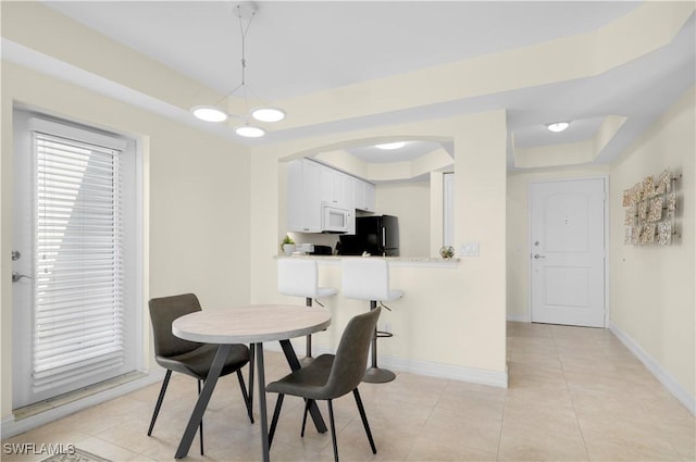 dining area with light tile patterned floors, a tray ceiling, and an inviting chandelier