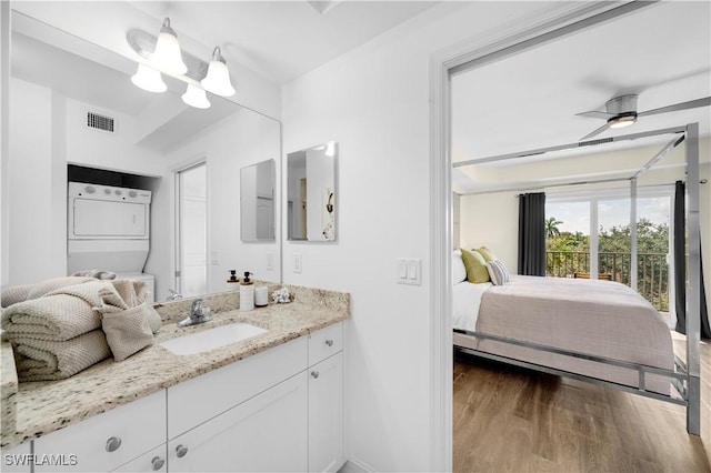 bathroom with stacked washing maching and dryer, ceiling fan, hardwood / wood-style floors, and vanity