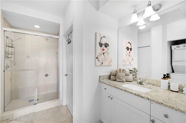 bathroom featuring a shower with door, stacked washer / drying machine, vanity, and tile patterned flooring