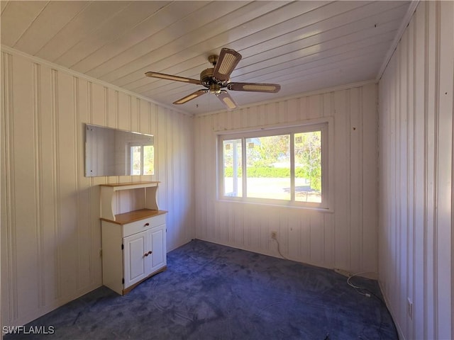 spare room with dark colored carpet, crown molding, and ceiling fan