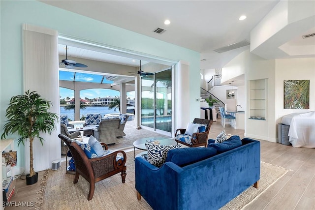 living room featuring ceiling fan, a water view, and light wood-type flooring