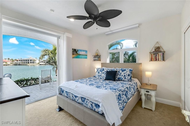 carpeted bedroom featuring ceiling fan, a water view, access to outside, and multiple windows