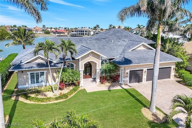view of front of home with an attached garage, decorative driveway, a front yard, and a water view