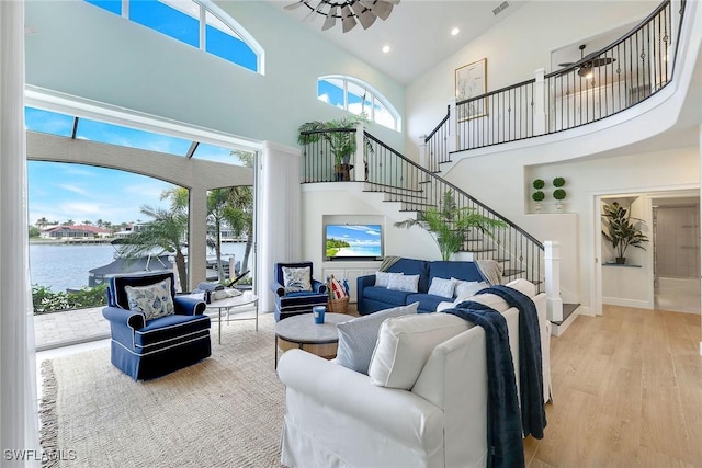 living room featuring a water view, stairway, recessed lighting, a high ceiling, and wood finished floors