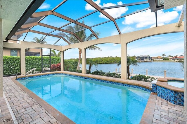 outdoor pool with glass enclosure, an in ground hot tub, a water view, and a patio