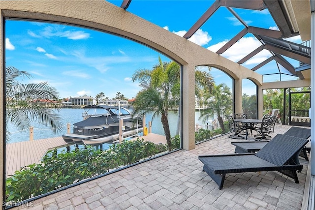 view of patio / terrace featuring boat lift, glass enclosure, a dock, and a water view