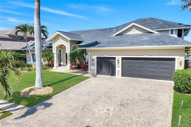 view of front of house with stucco siding, an attached garage, decorative driveway, and a front yard