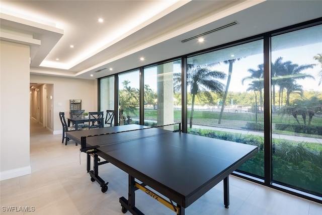 recreation room with expansive windows and a raised ceiling